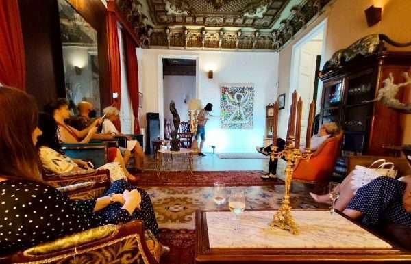 A full shot of the room with Miroslavo at the end of the room presenting his painting Independence.